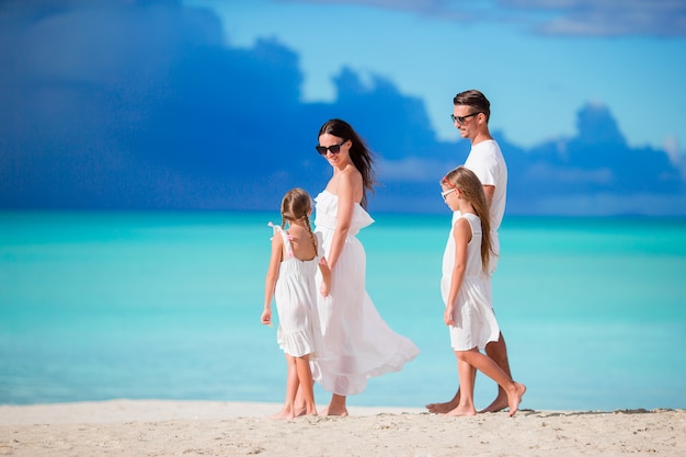 Family of four walking on white beach