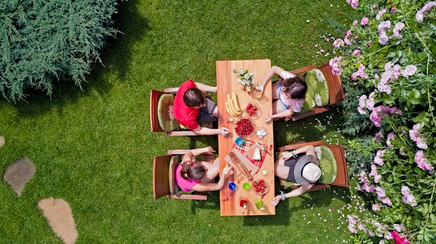 Family and friends eating together outdoors on summer garden party. Aerial view of table with food and drinks from above. Leisure, holidays and picnic concept