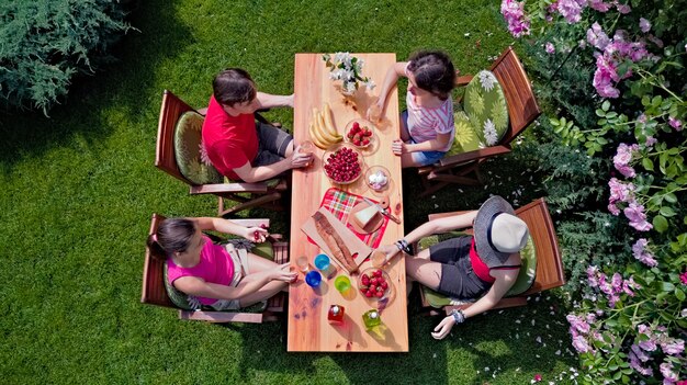 Family and friends eating together outdoors on summer garden party