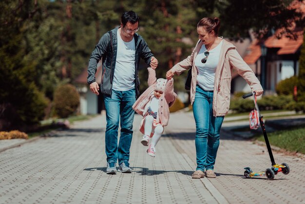 Family fun in the park. Happy family spending time in park and playing with their daughter.