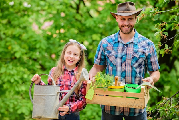 family garden. maintain garden. planting flowers. family dad and daughter planting plants. transplanting vegetables from nursery or gardening center. plant your favorite veggies. planting season.