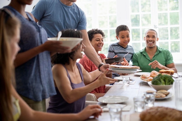 A family gathering men women and children around a dining table sharing a meal