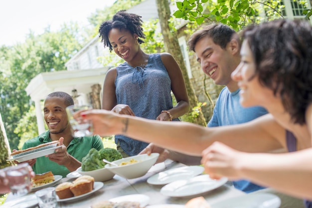 A family gathering men women and children around a table in a garden in summer