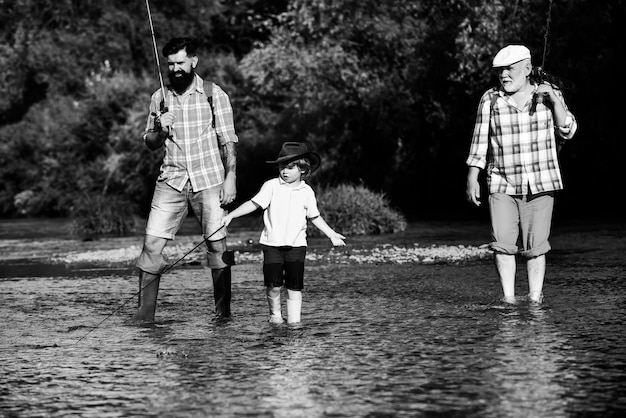 Family generation and people concept boy with father and grandfather fly fishing outdoor over river