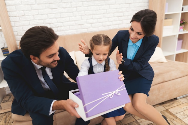 Famiglia che dà regalo alla figlia sul divano a casa