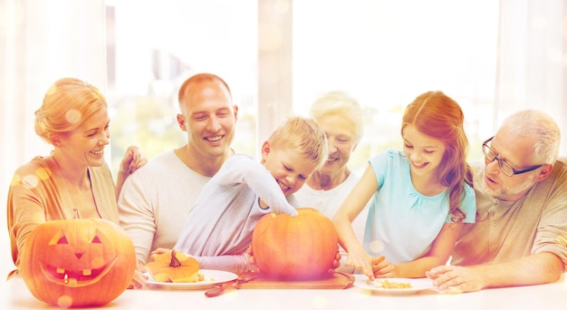 Concetto di famiglia, felicità, generazione, vacanze e persone - famiglia felice che fa zucche di halloween a casa