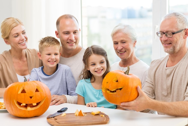 family, happiness, generation, holidays and people concept - happy family making halloween pumpkins at home