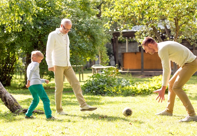 写真 家族、幸福、世代、家と人々の概念-屋外の家の前でサッカーをする幸せな家族