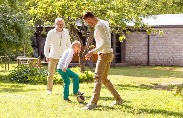 семья, счастье, поколение, дом и концепция людей - счастливая семья играет в футбол перед домом на открытом воздухе