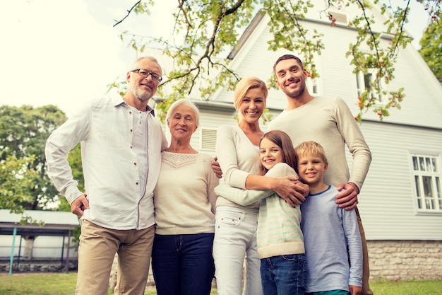 가족, 행복, 세대, 가정 및 사람 개념 - 야외에서 집 앞에 서 있는 행복한 가족