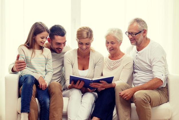 Photo family, happiness, generation and people concept - happy family with book or photo album sitting on couch at home