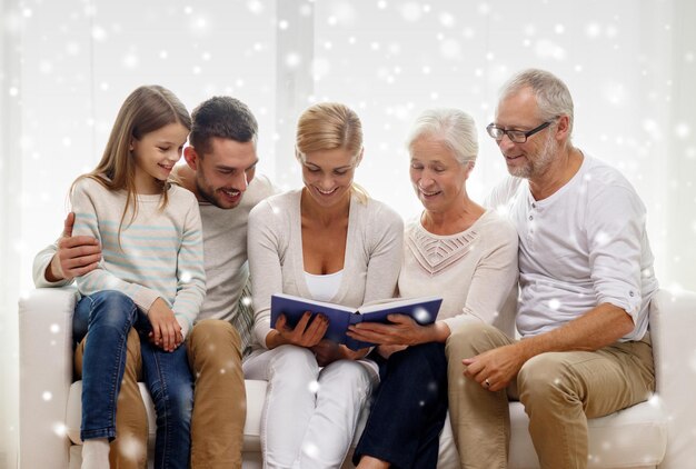 가족, 행복, 세대 및 사람 개념 - 집에서 소파에 앉아 책이나 사진 앨범을 가진 행복한 가족