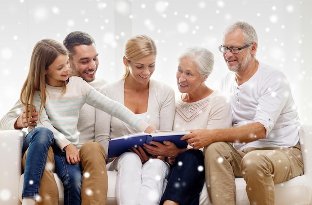 Photo family, happiness, generation and people concept - happy family with book or photo album sitting on couch at home