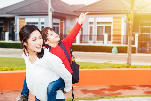 Family happy children kid son boy kindergarten ride back piggyback mother mom on park