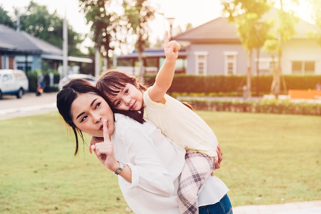 family happy children kid son girl kindergarten playing ride back piggyback mother mom on outdoors park
