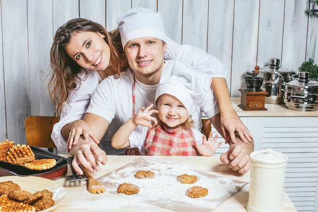 Foto famiglia, figlia felice con papà e mamma nella cucina di casa ridendo e preparando il cibo insieme, con amore