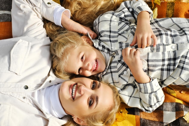 Foto la famiglia si diverte nel parco la ragazza e la madre giacciono su una coperta sorridono e guardano la macchina fotografica