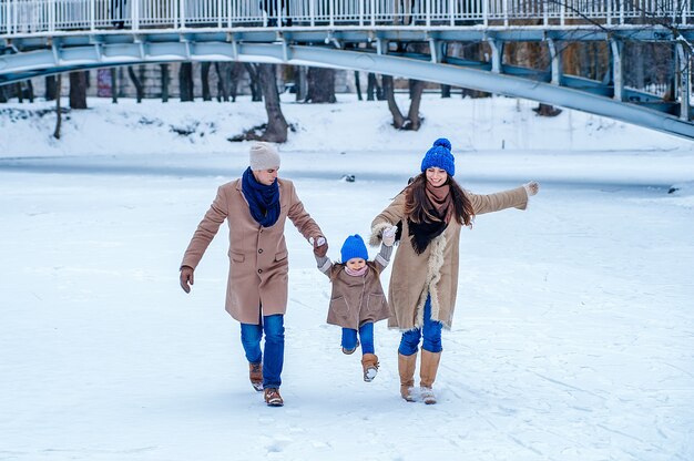 Family have fun on a frozen lake in the park against the background of the bridge