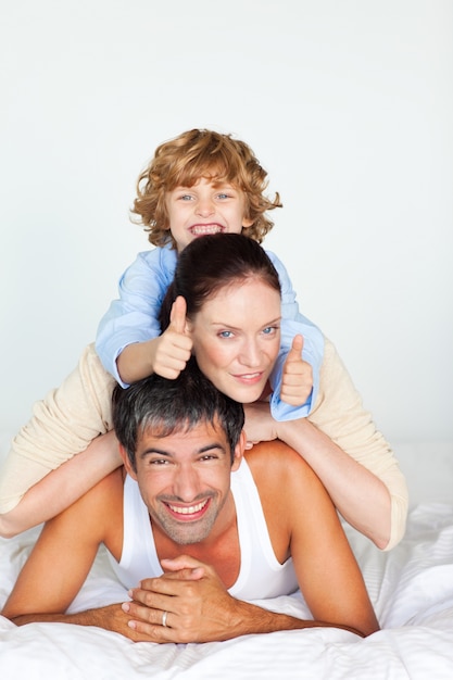 Family having fun in bed with thumbs up 