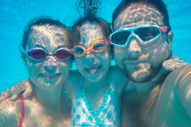 Family having fun in swimming pool Underwater funny portrait Summer vacation