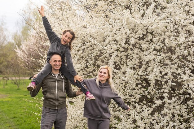 family having fun with flowering tree in blooming spring garden.