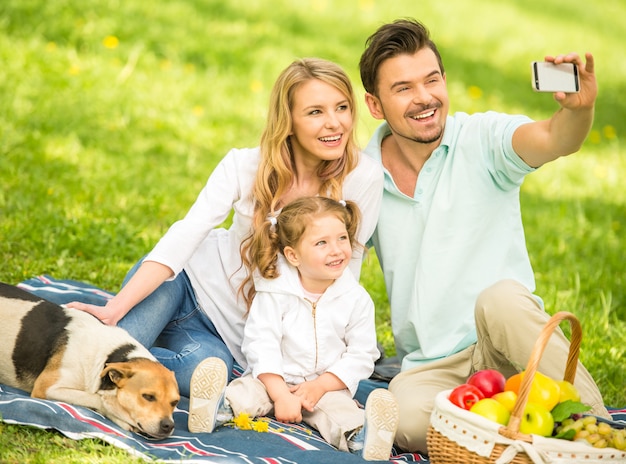 Famiglia avendo picnic all'aperto e facendo selfie.