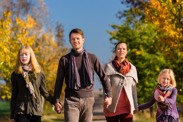 Family having walk in front of colorful trees in autumn