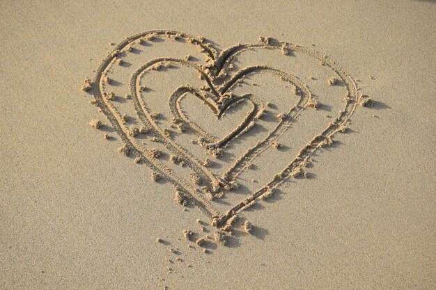 Photo family of hearts drawn on the sand of the beach