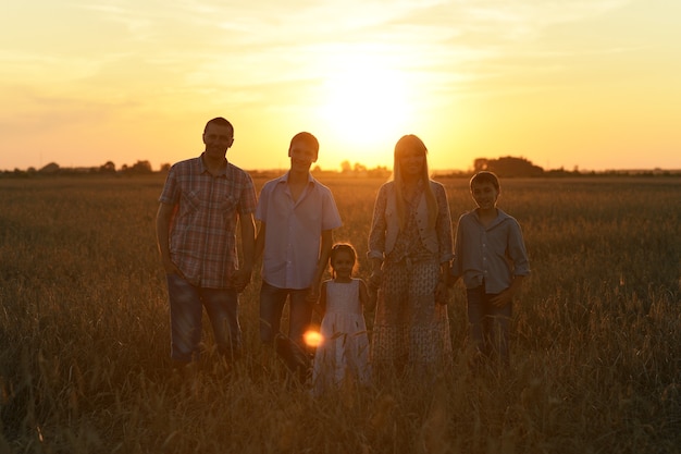 Photo family holding hands looking at sunset in field