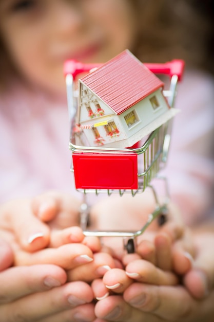 Family holding little house in shopping cart Shallow depth of field