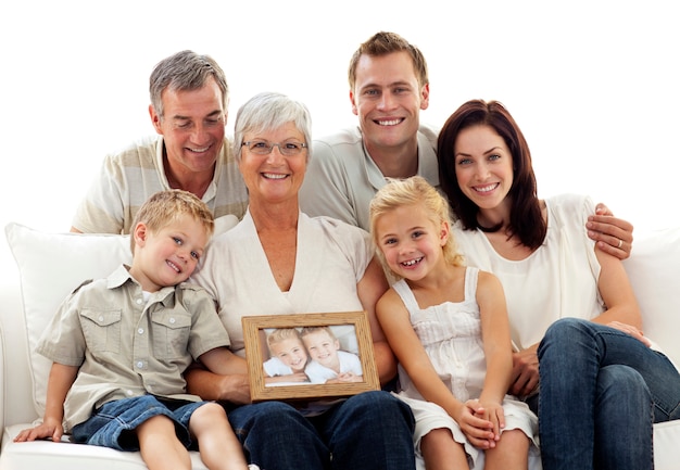 Family holding a portrait of children sitting on sofa