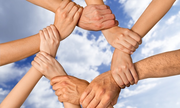 Family holding their hands together in shape of sun with sky on background