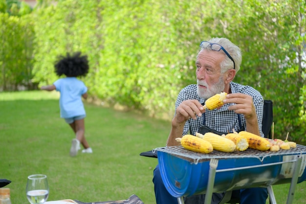 Family holiday activities with grandfather mother and children with camping bbq grill and play in the yard together happily on vacation