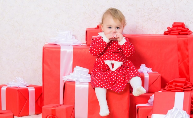가족 휴가. 유아를 위한 크리스마스 선물. 아이의 첫 크리스마스 선물. 첫 번째 크리스마스를 축하합니다. 일생에 한 번뿐인 베이비 퍼스트 크리스마스 이벤트. 작은 아기 소녀는 선물 상자 더미 근처에서 재생합니다.