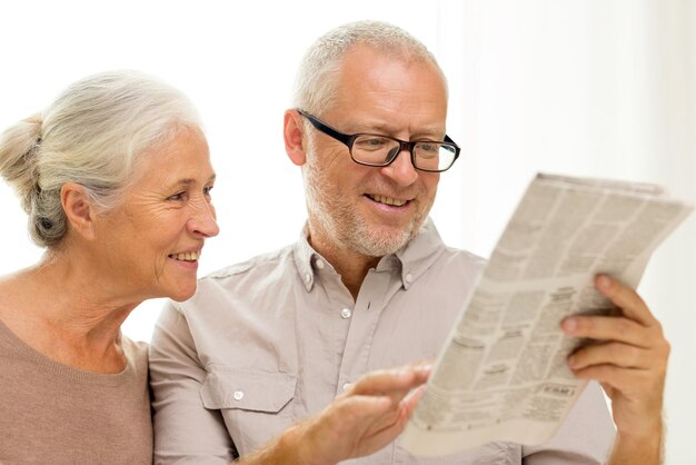 family, holidays, age and people concept - happy senior couple reading newspaper at home