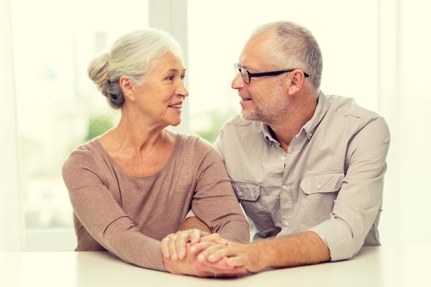 family, holidays, age and people concept - happy senior couple sitting on sofa at home