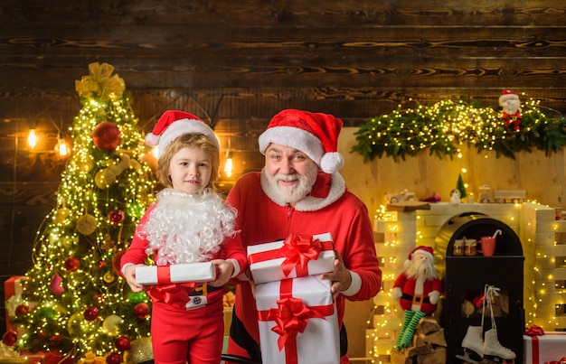 Family holidays and childhood concept little child with santa claus and christmas gift at home santa