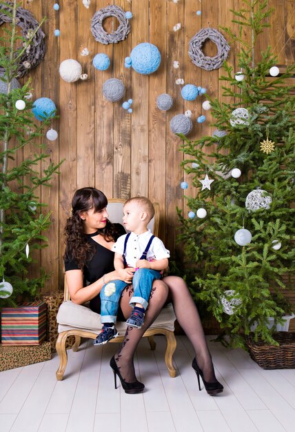 Family, holidays and christmas concept - mother and son near the christmas tree