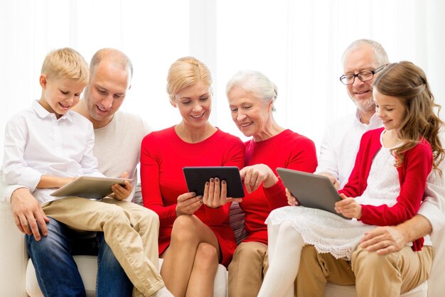 family, holidays, christmas, technology and people concept - smiling family with tablet pc computers sitting on couch at home