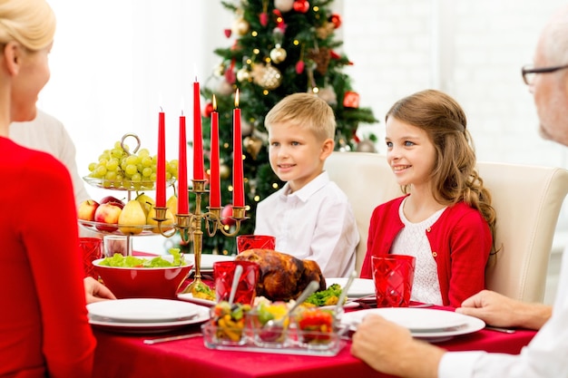 Concetto di famiglia, vacanze, generazione, natale e persone - famiglia sorridente che cena a casa