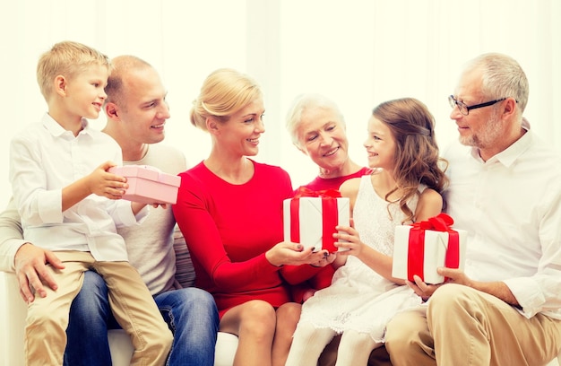 가족, 휴일, 세대, 크리스마스, 사람 개념 - 집에서 소파에 앉아 선물 상자를 들고 웃고 있는 가족