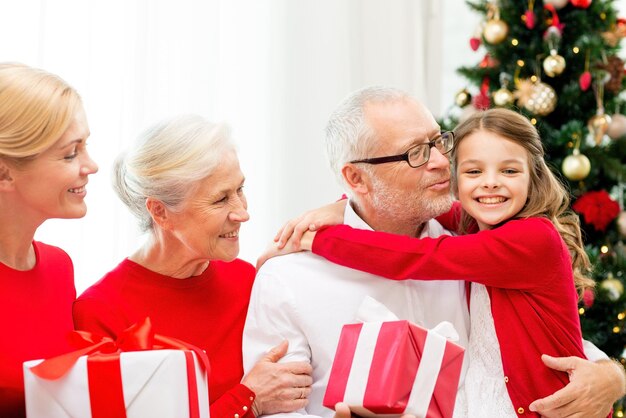 家族、休日、世代、クリスマス、人々のコンセプト-自宅のソファに座っているギフトボックスを持つ笑顔の家族