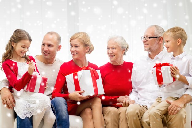 family, holidays, generation, christmas and people concept - smiling family with gift boxes sitting on couch at home