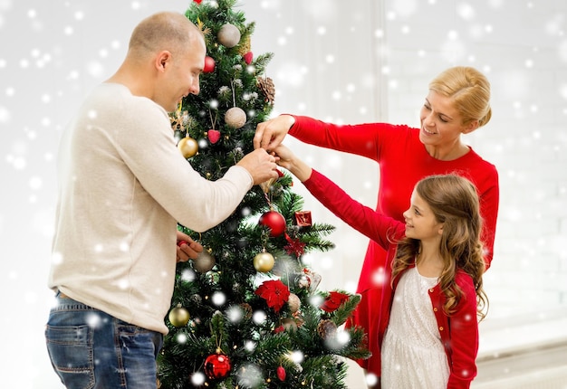 family, holidays, generation and people concept - smiling family decorating christmas tree at home