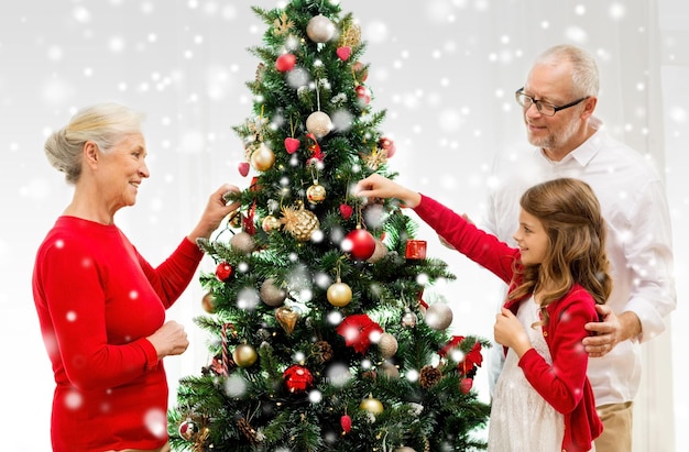 family, holidays, generation and people concept - smiling family decorating christmas tree at home