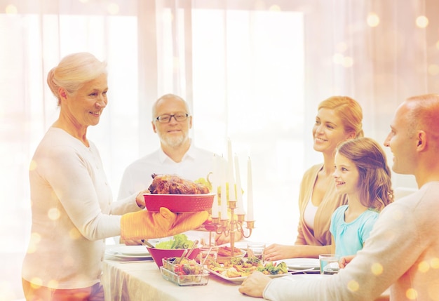 family, holidays, generation and people concept - smiling family having dinner at home