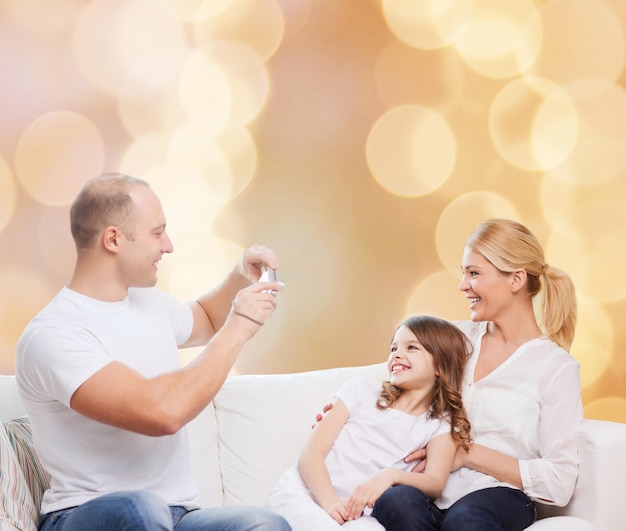 家族、休日、テクノロジー、人々のコンセプト-ベージュのライトの背景にカメラで笑顔の母、父、少女