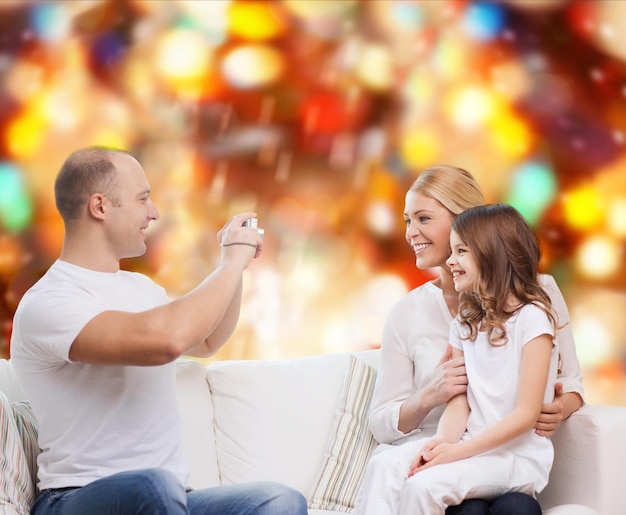 가족, 휴일, 기술, 사람 개념 - 웃는 어머니, 아버지, 그리고 빨간 조명 배경 위에 카메라를 들고 있는 어린 소녀