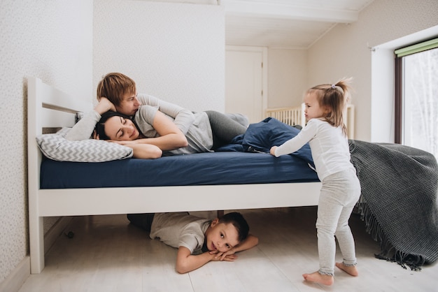 Famiglia a casa in pigiama. figlia e figlio. svegliati la mattina abbracciarsi e baciarsi nella camera da letto sul letto.