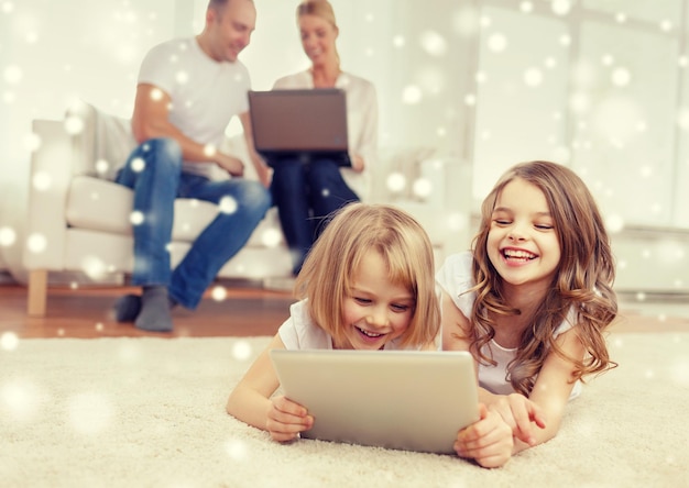 family, home, technology and people - smiling mother, father and little girls with tablet pc computer over snowflakes background